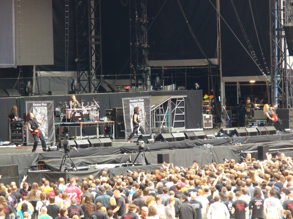 a crowd of people standing around a stage with some guitar playing