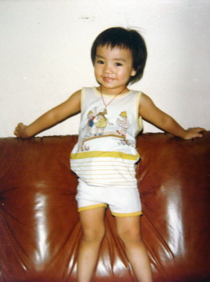 small child with very large chest standing in front of a couch