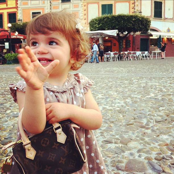 a little girl is waving and smiling for the camera