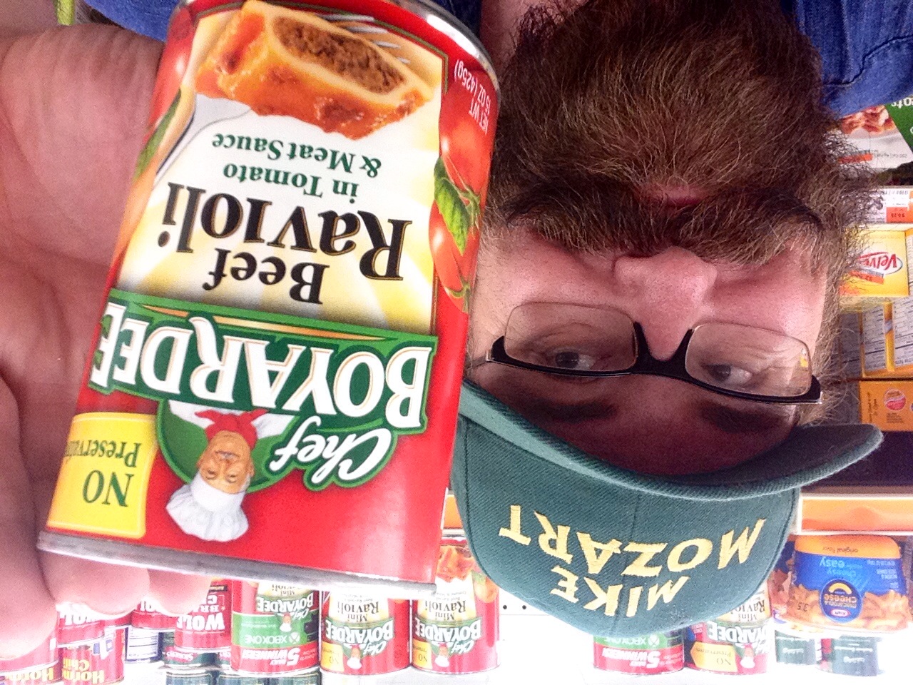a bearded man is holding up his canned beef ravioli