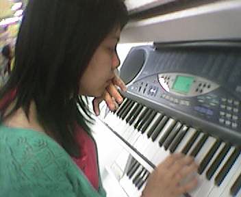 a girl is putting a pen into her mouth and playing piano