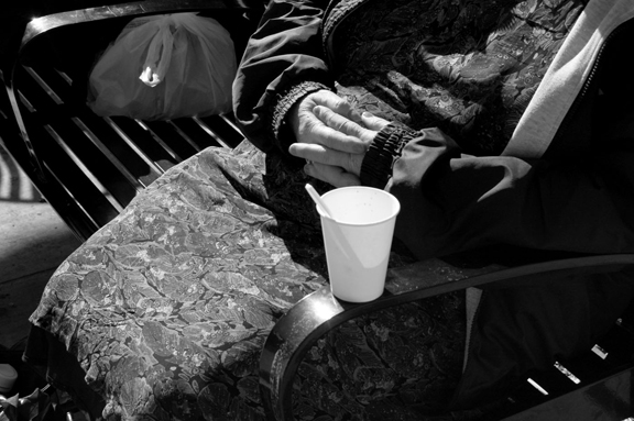 a person with a drink sits on a bench
