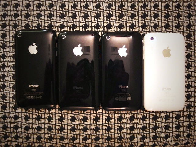 four apple cell phones lined up in a row