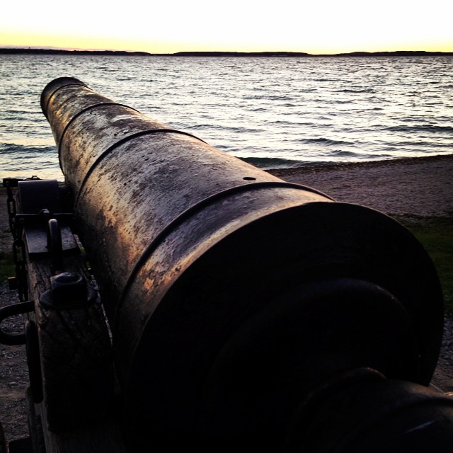 a long pipe sitting by the ocean with an island in the background