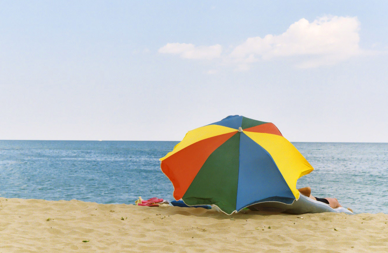 a beach umbrella is opened on the sand near water