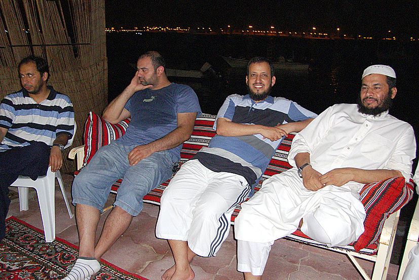 four men sitting on a bench with their arms wrapped around them