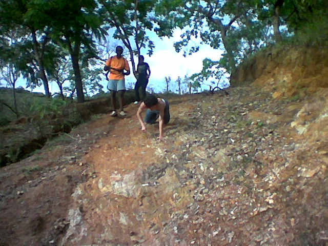 two men on a dirt hill with trees and rocks