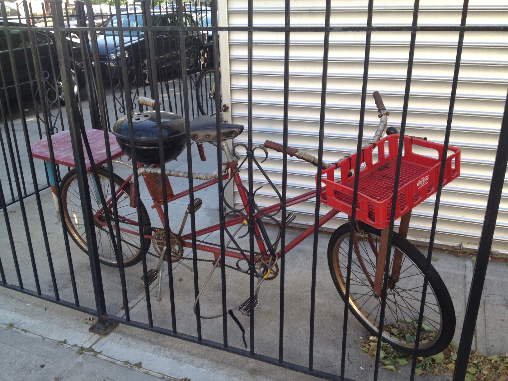 a bicycle locked to the side of a street behind a fence