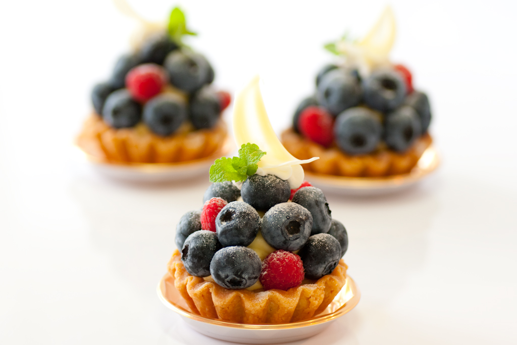 two small cupcakes are decorated with berries and cream