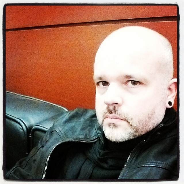 a man with a bald head sitting in a black chair