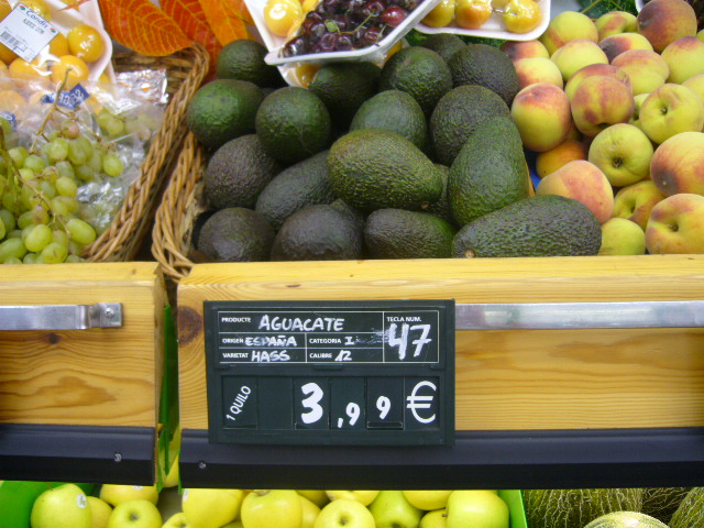 a fruit stand that contains lots of apples and avocados