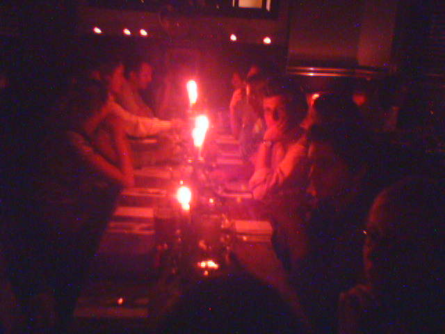 people sitting around a table, lighting candles on them
