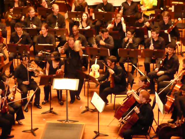 orchestra members holding their instruments and waving