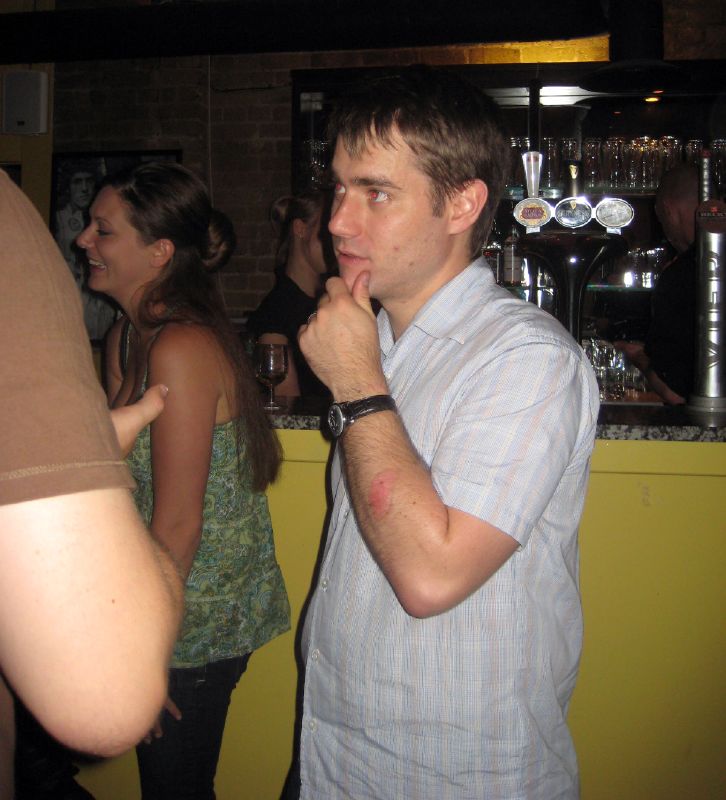 man standing in front of a bar making a gesture