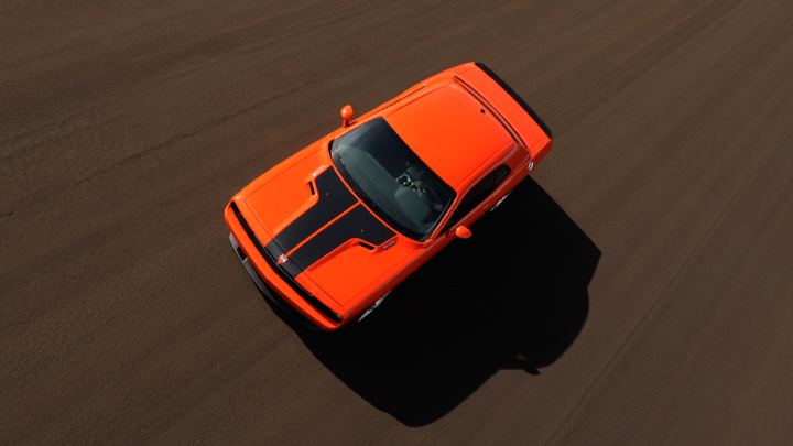 an orange, two - door, three - seat vehicle is going down a track