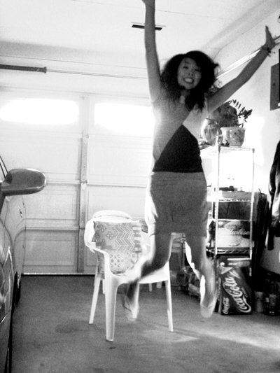 a woman jumping off of a chair with a car in the background