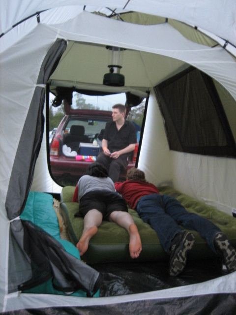 a couple of people laying on top of a green bed in a tent