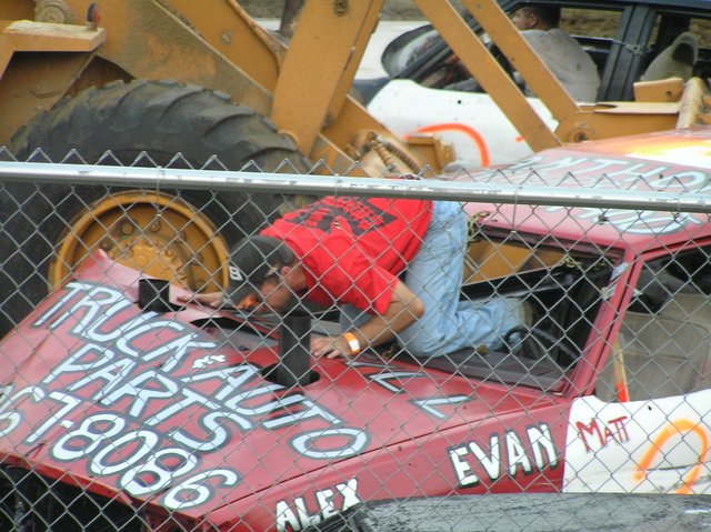 a worker fixing an old car in a junkyard
