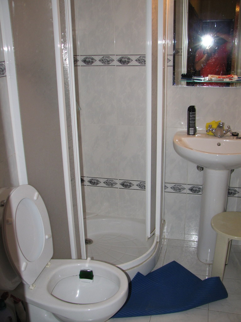 the interior of a bathroom with the shower door and toilet seat cover