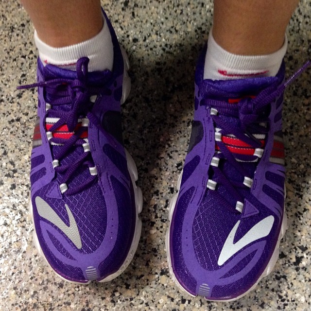 person's feet in purple and white shoes on a granite floor
