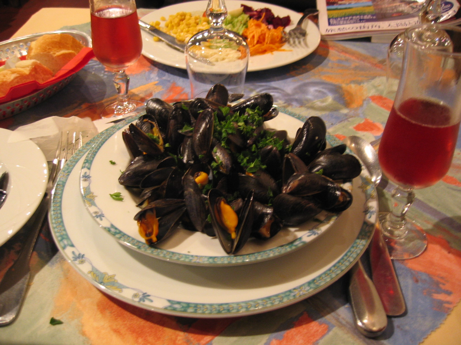 a plate topped with lots of mussels next to salad