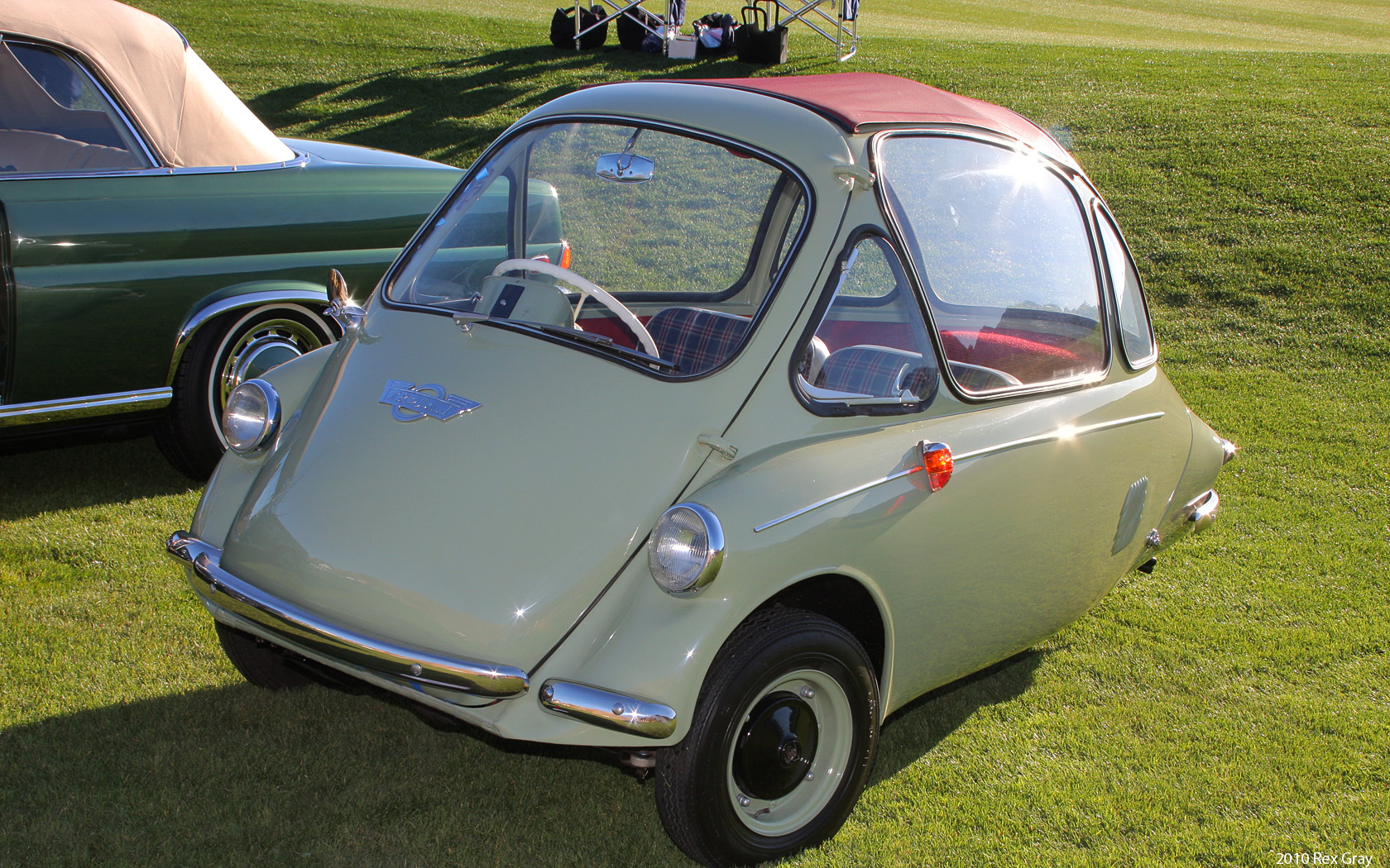 an old, green car sits next to an older car