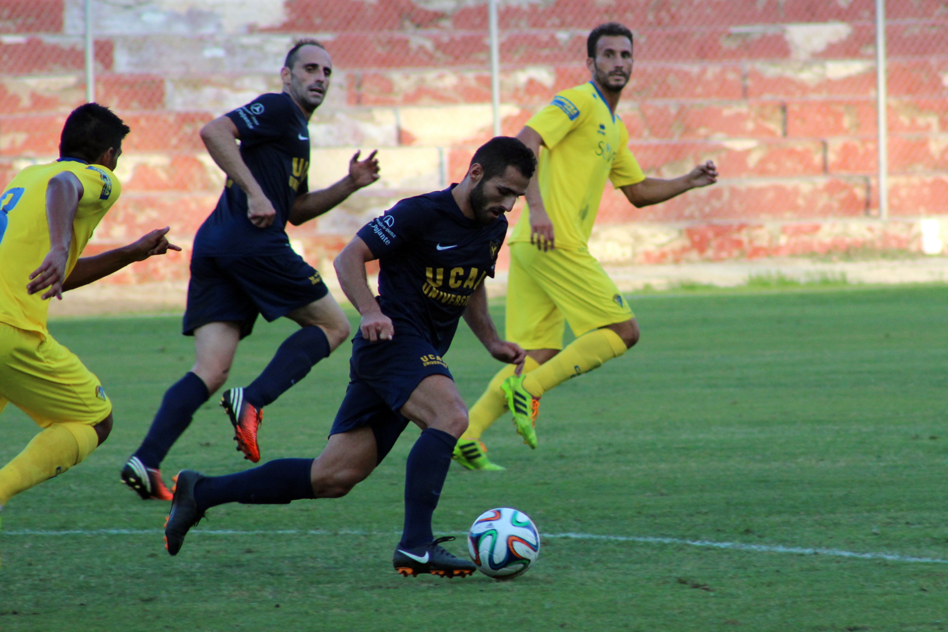 soccer players running for the ball in a game