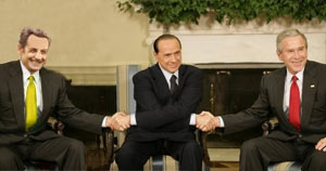 three men sit on a chair in suits and ties