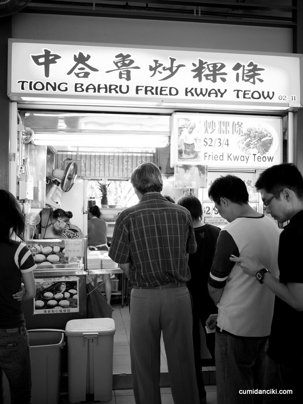 several people standing outside of a restaurant looking at items