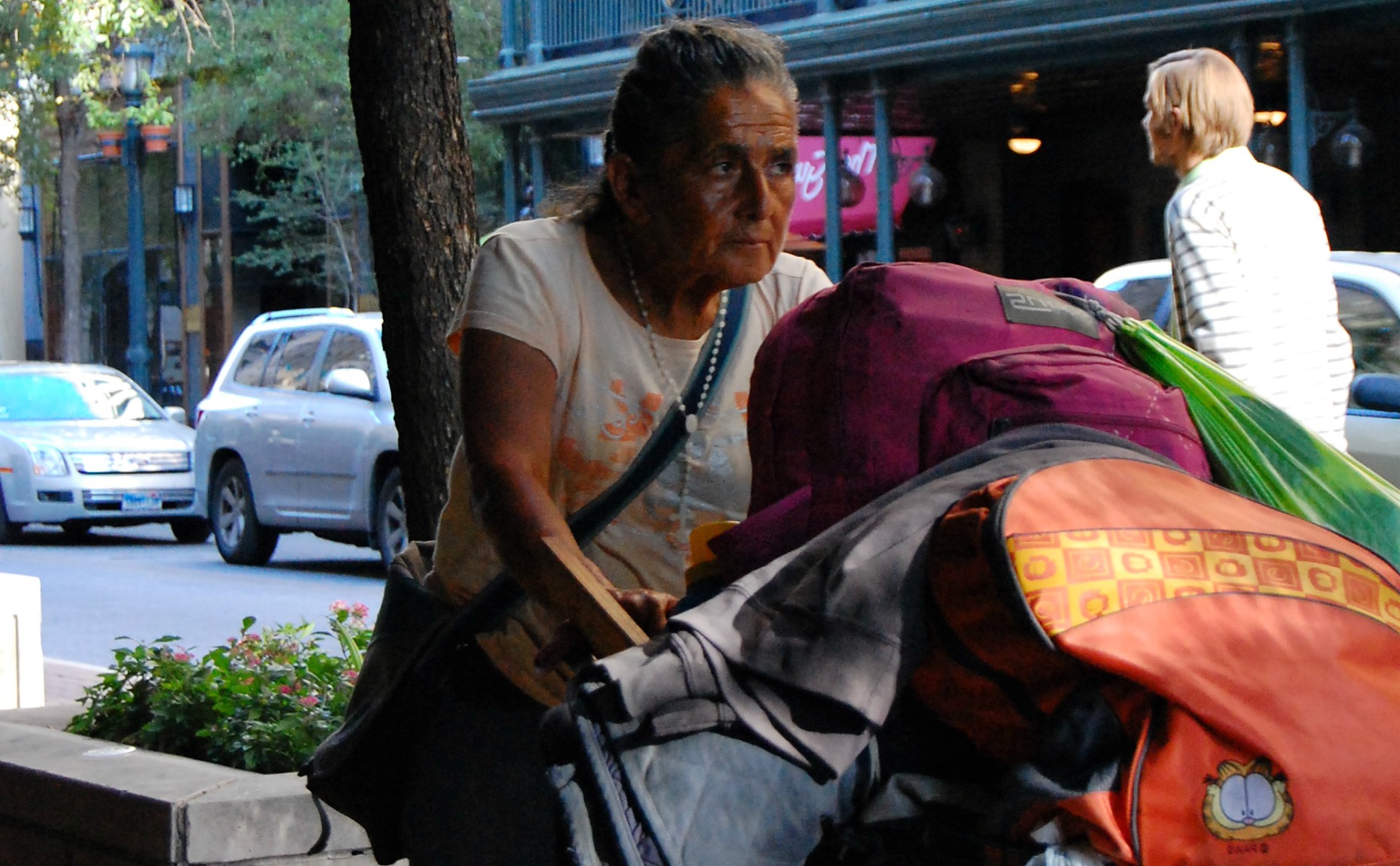 an older woman sitting outside with her bags