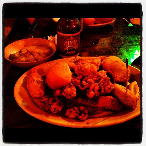 a plate filled with fried food and two beer bottles