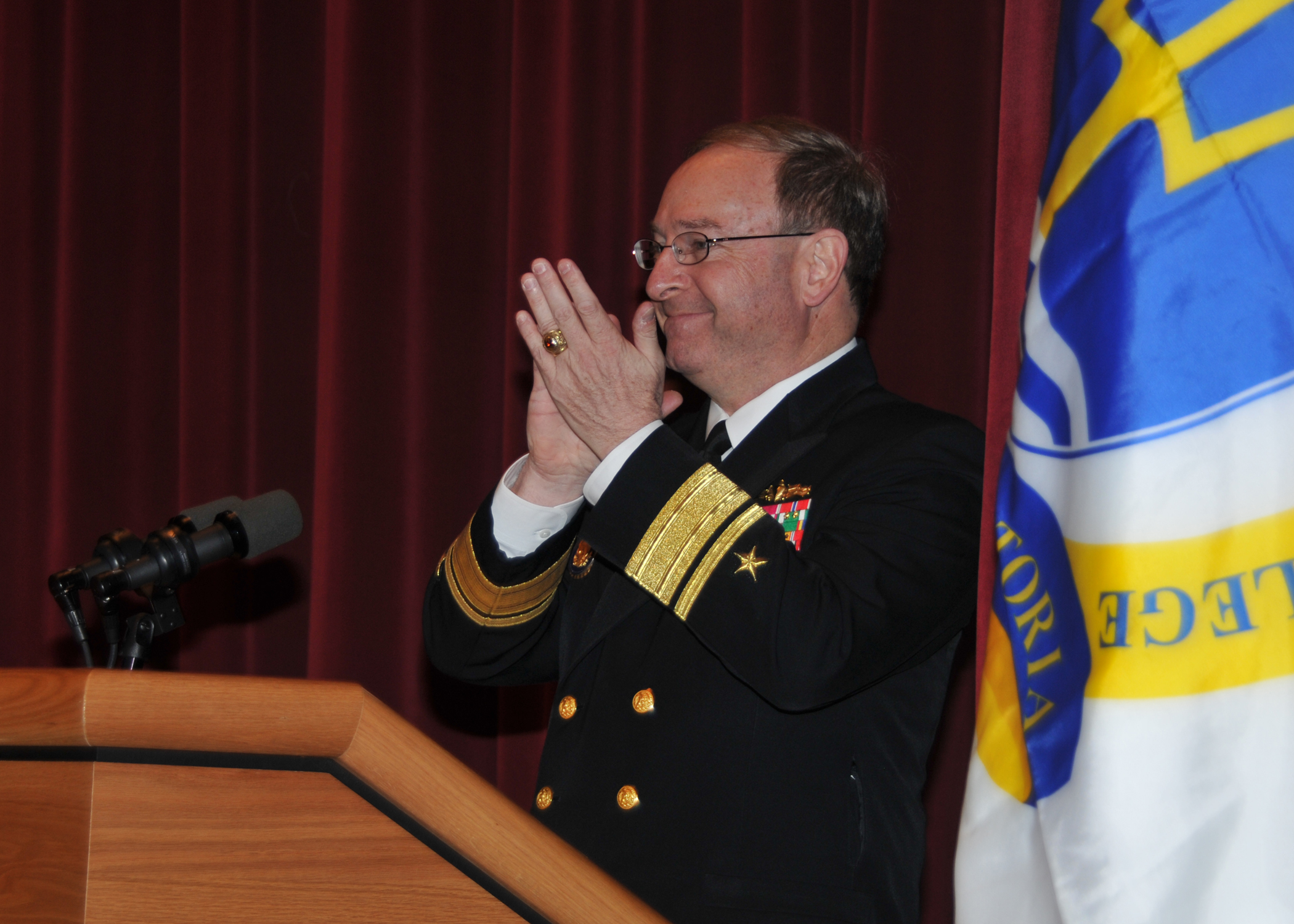 a man in military dress clothes clapping behind a podium