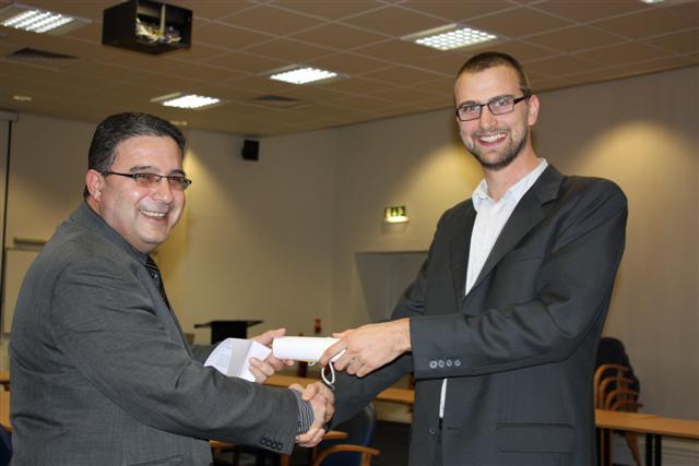 two men shaking hands while smiling at the camera