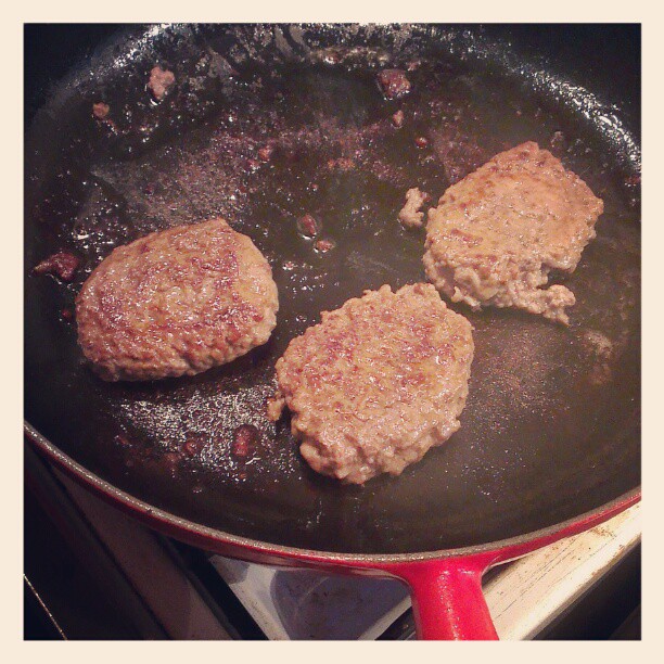 three hamburger patties cooking in a set on the stove
