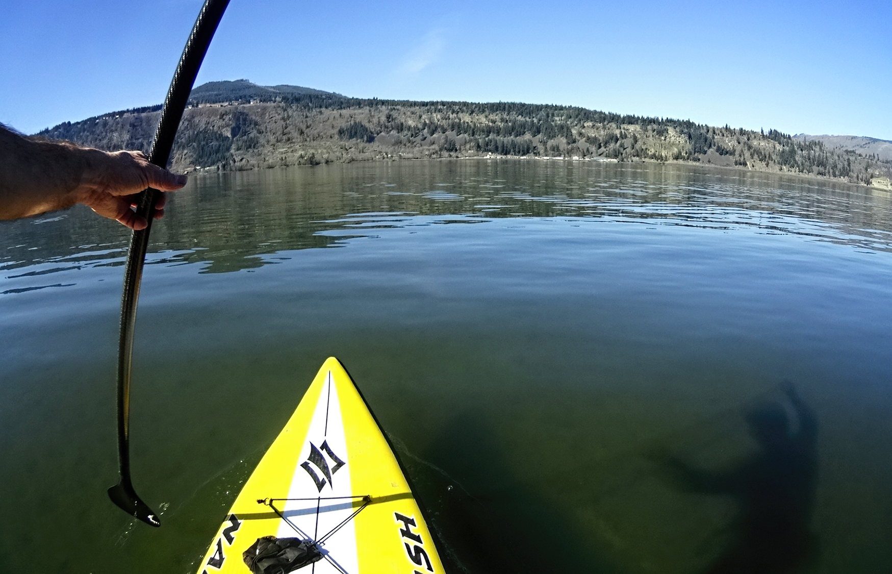 the view from a kayak of a mountain range and a man's hand holding an oar on water