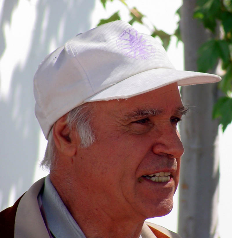 a man wearing a white hat and jacket looks off into the distance