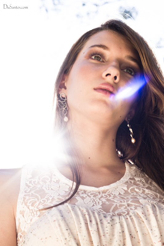 woman standing under sunlight in white dress near nches