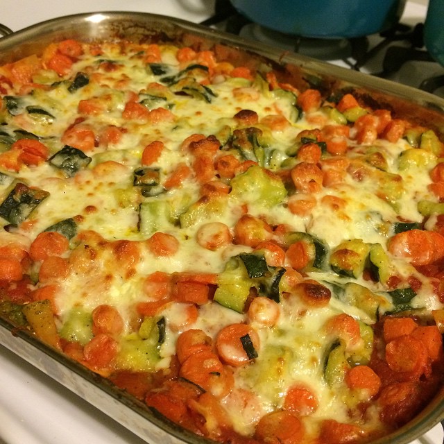 a pan with a casserole covered in tomato, green peppers, and sausage
