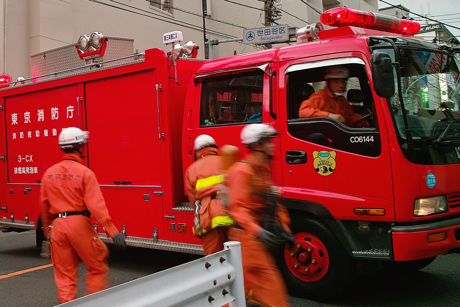 men in orange work around a firetruck that has some workers in orange work attire on