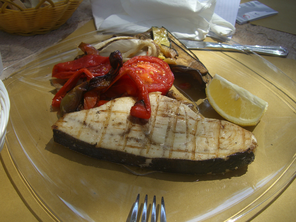 a plate topped with meat, vegetables and a lemon slice