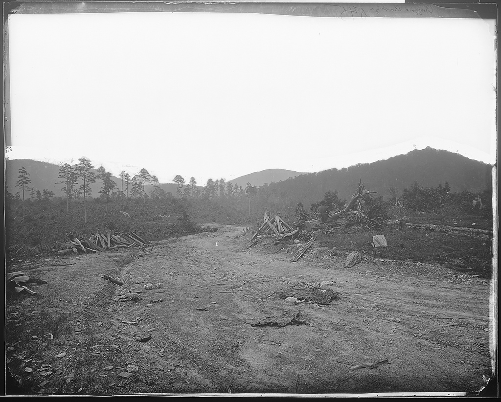 a view of a dirt field with mountains in the background