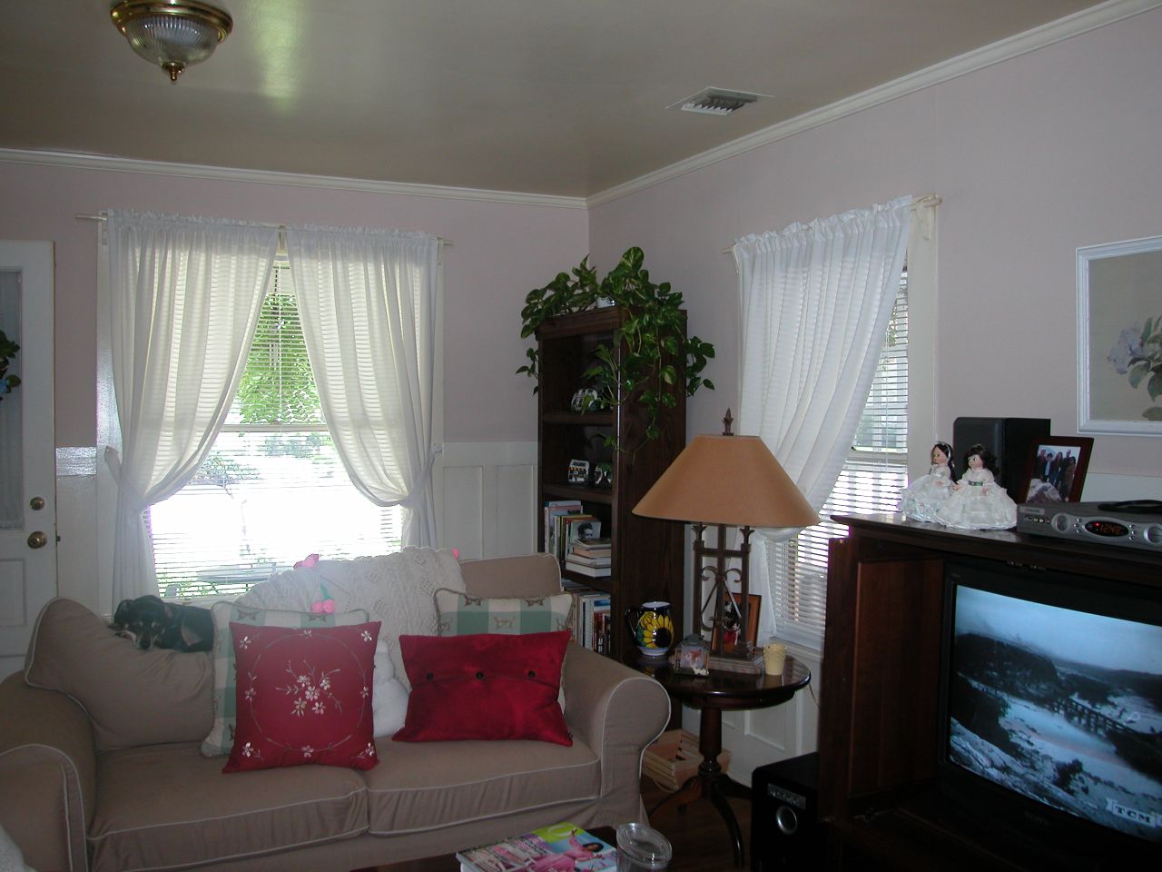 a living room with white curtains and a large tv