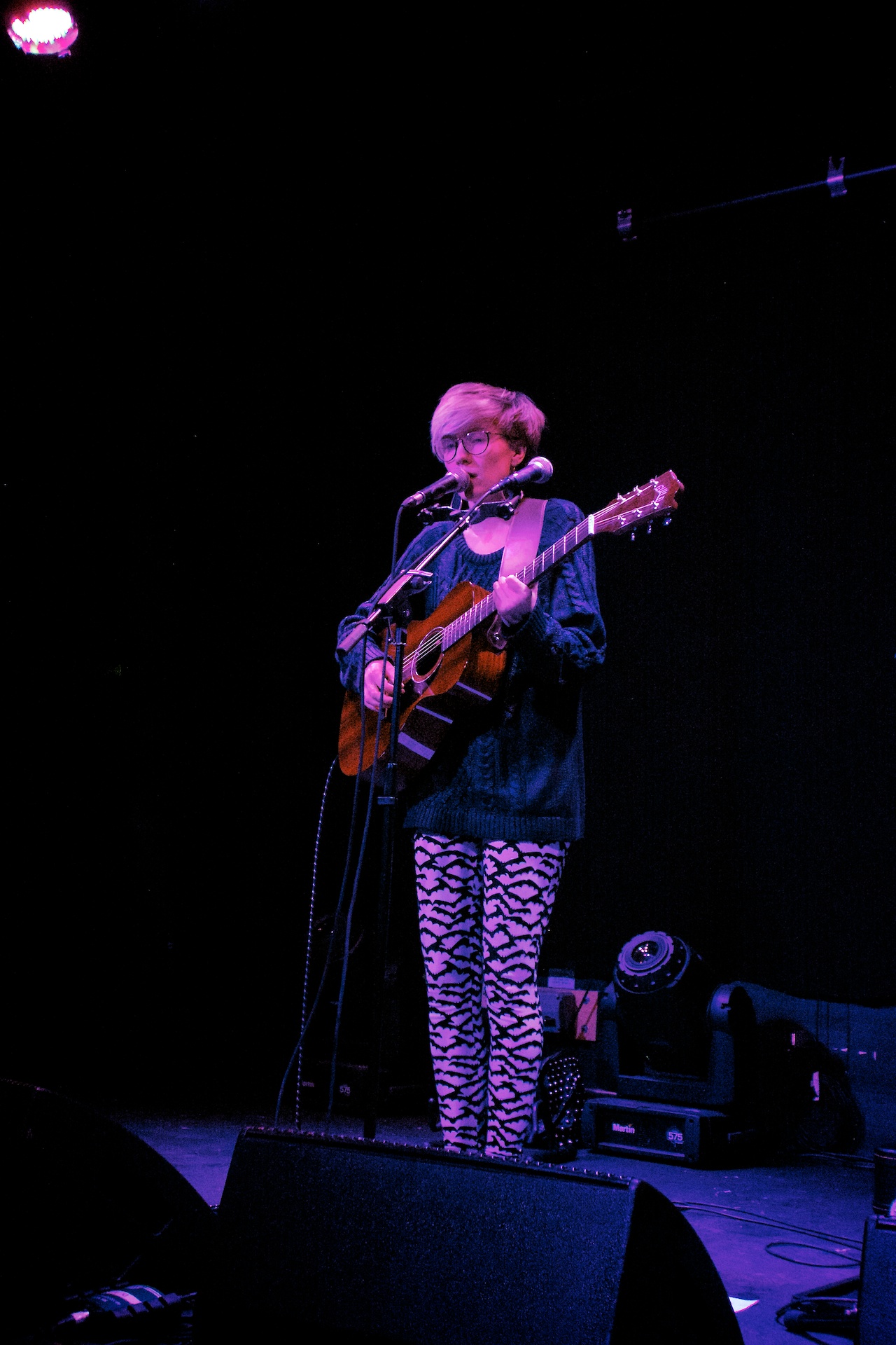 a woman singing on stage playing the guitar