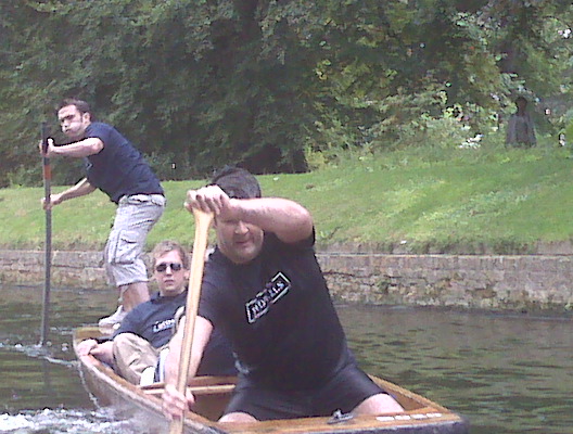 two men riding in a small boat, one rowing