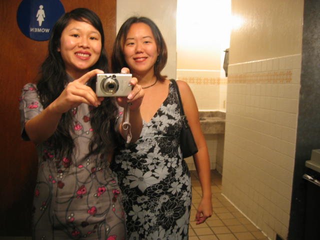 two asian women take a picture with their camera in the bathroom