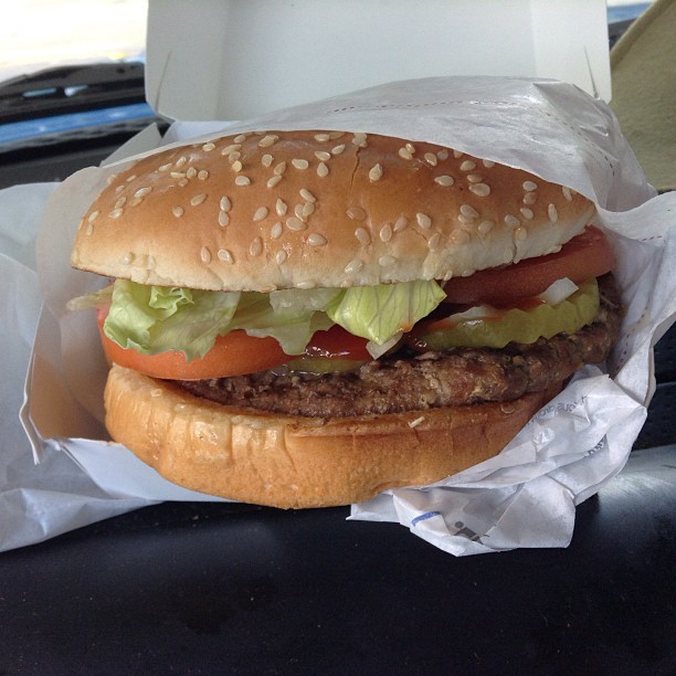 a hamburger sitting in a plastic container with wrapper