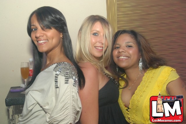 three young ladies standing together at a party