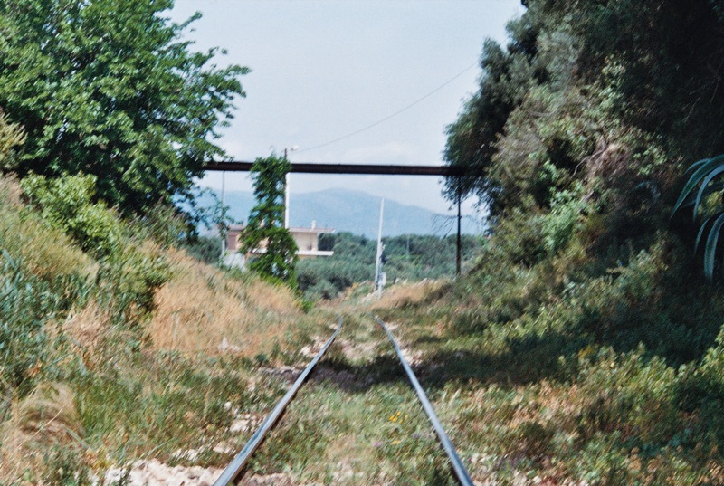 a train track on a mountain side that is passing under an elevated bridge