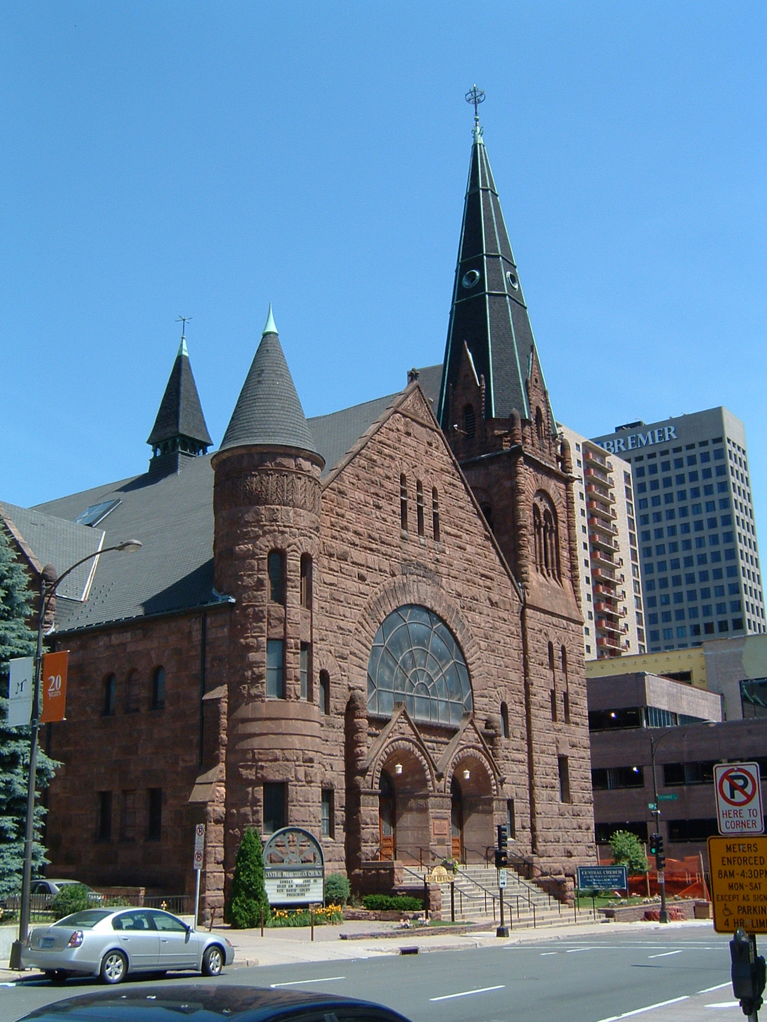 a large brick building with tall steeples stands next to a street