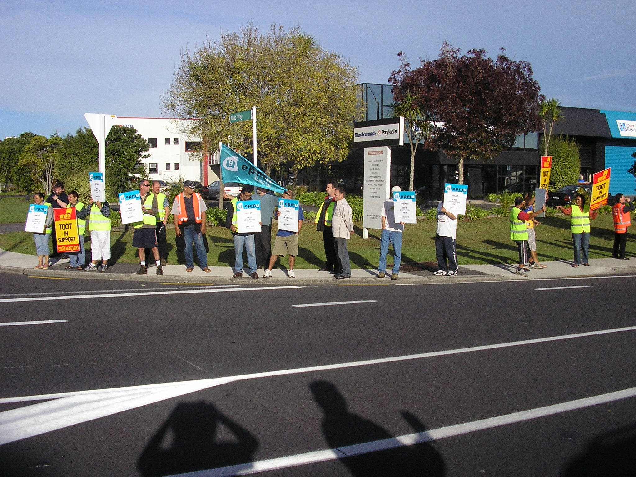 some people standing on the side of the road with signs